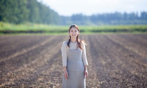 畑の前に立つ女性