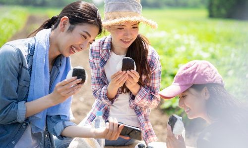 自然のなかでおにぎりを食べる女性たち