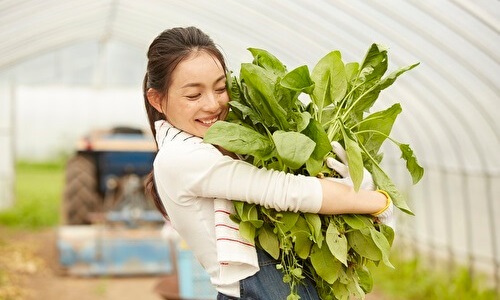 収穫物を抱える女性農家