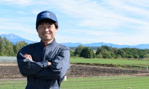 農地を背景に微笑む農家男性