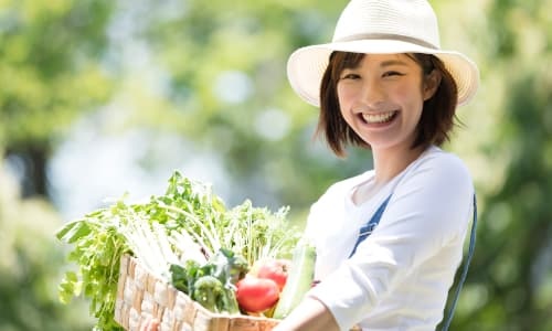 かご一杯の野菜を抱えている女性