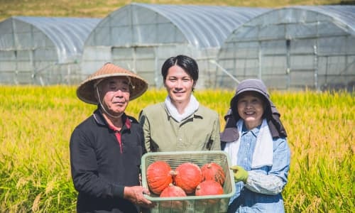 ビニールハウスの前で記念撮影をする農業一家