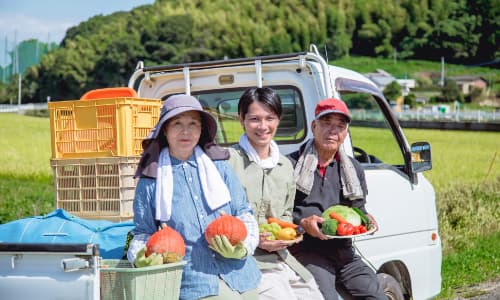 地元農家と一緒に軽トラックに腰かけている脱サラ農家